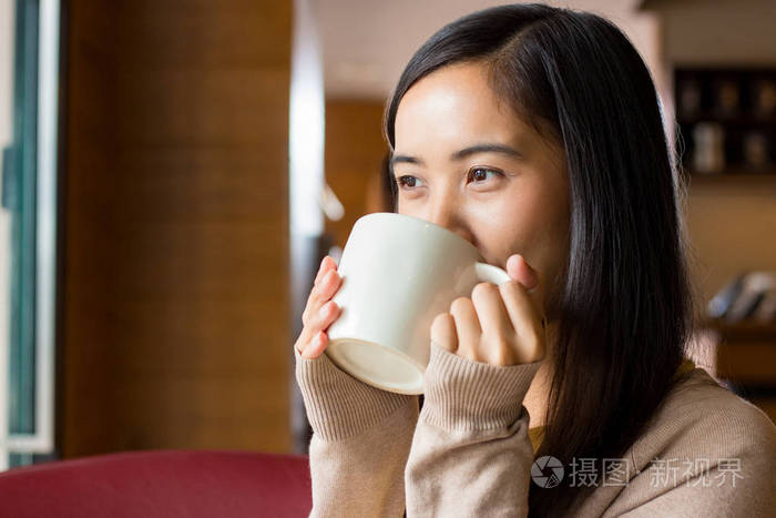 亚洲女人从白咖啡杯子喝咖啡