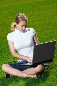 绿色草坪上有笔记本电脑的女孩
