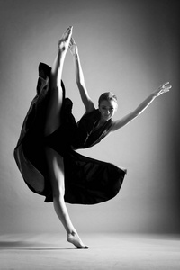 在一件黑色连衣裙的美丽运动女孩跳舞在跳
