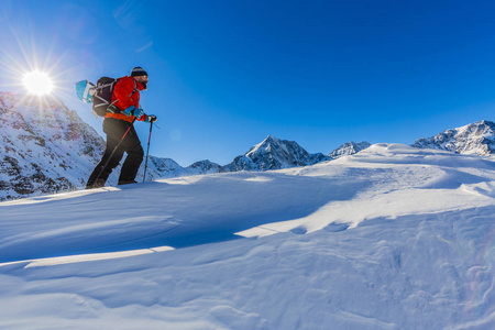 冬山攀爬到顶部在阳光下的雪鞋的徒步旅行者
