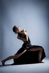 一个漂亮的运动女孩穿着黑色的连衣裙跳舞