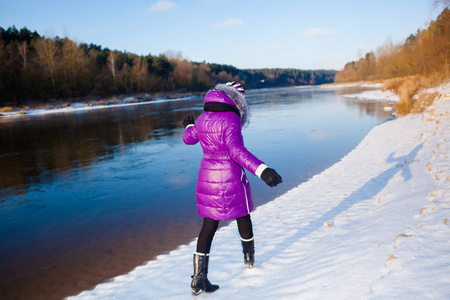 十几岁的女孩走在冬天冰冻的河银行