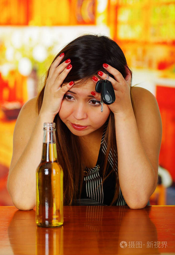 一个醉酒的女人与两个肖像手在她的头看一瓶啤酒和钥匙在她手中在酒吧