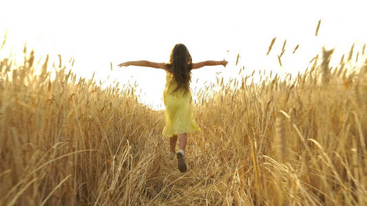 年轻的女孩穿着奔跑着穿过田地