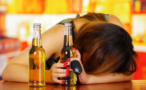 在一张木桌和持有开放的啤酒和车钥匙,用她的手,在酒吧背景的肖像照片