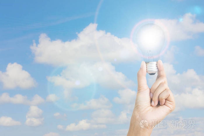 手拿灯泡与镜头光晕着蓝蓝的天空背景上在左边的copyspace生态权力