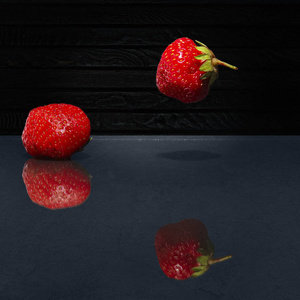 新鲜草莓与玻璃在黑暗背景下的思考