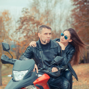 美丽的夫妇，与一辆摩托车在日落时