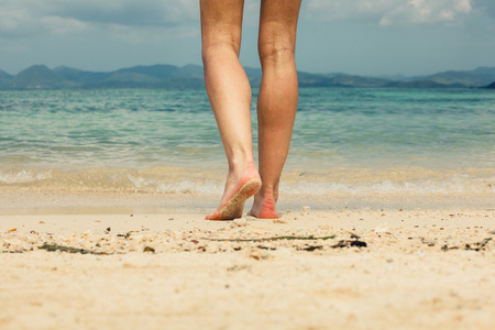 脚和腿的年轻女子在沙滩上行走照片