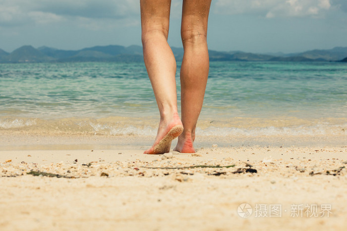 脚和腿的年轻女子在沙滩上行走