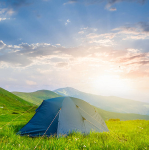 日落时的绿色山间旅游帐篷