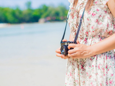 女人控股相机和上海滩海边行走。夏天和度假概念