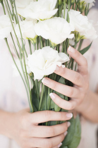 年轻的女孩手里拿一大束的白色鲜花。明亮的女性生活方式