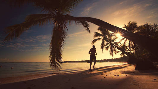 海上日出。男人在热带岛屿上运行海滩蓬塔卡纳