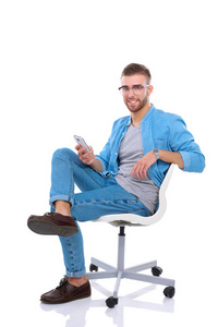 年轻男子坐在椅子上，并使用移动电话。Startupper。年轻的企业家