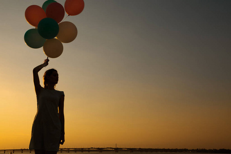 飞翔天空的气球的年轻女子的剪影