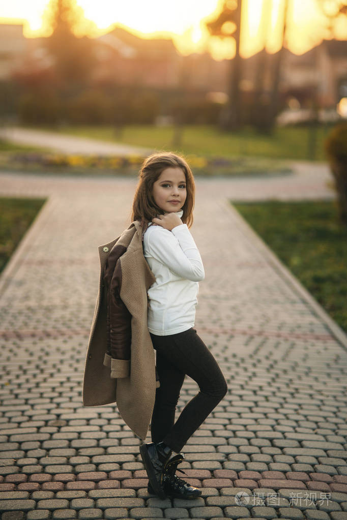 在秋天外套为摄影师摆姿势的小女孩金色的秋天