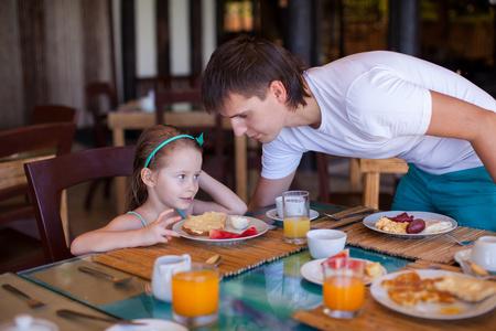 父亲和小女孩一起吃早餐在户外咖啡馆