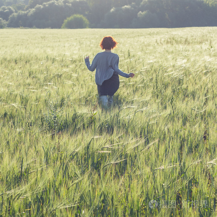 女孩在早上跑步穿过绿色的田野
