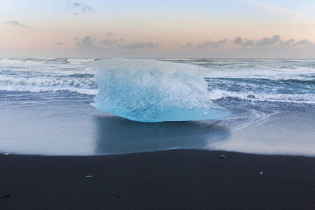 在冬末，冰岛在黑沙海滩上打破冰山