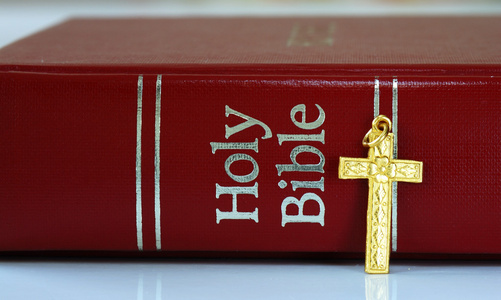红色圣经旁边的一个金十字架