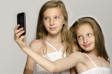 两个年轻姑娘把自拍照，拍张照片，开心，女孩子在玩手机的孩子