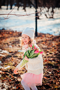 春天的郁金香花束上的走在阳光灿烂的日子快乐微笑的孩子女孩画像
