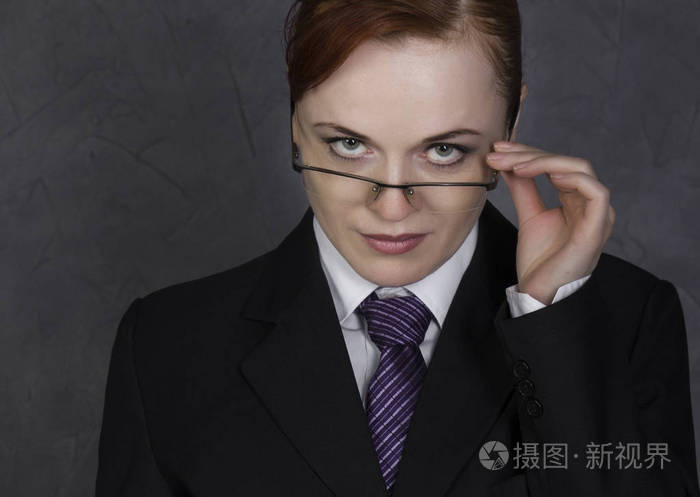 女律师拿着严肃的表情,女人在大书勒芒西装, 领带, 眼镜等