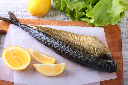 熏制 mackerele 和柠檬绿色的莴苣叶上木菜板上白色背景孤立