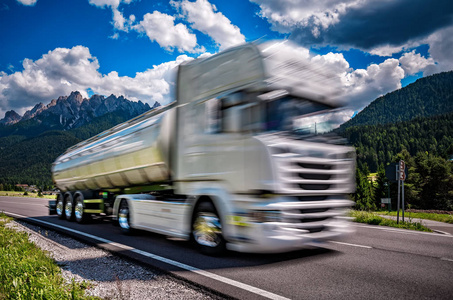 燃料卡车冲下来在背景阿尔卑斯山的公路。T
