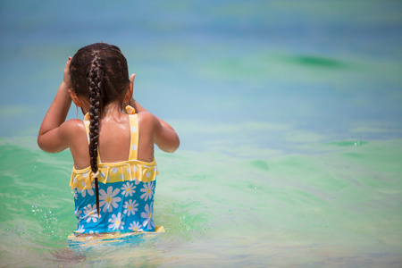 快乐的小姑娘，在泳装在清澈的海水中获得乐趣
