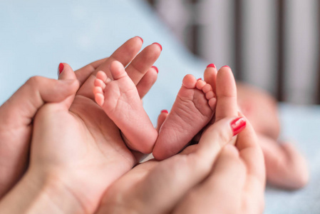 宝宝脚在母亲的手中。新生宝宝小脚上女性异型手特写。妈妈和她的孩子。快乐家庭的概念。美丽的概念形象的产假