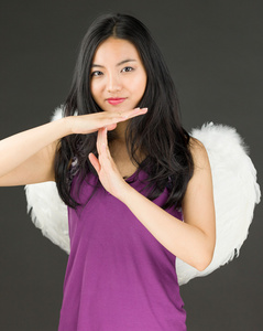 年轻的亚洲女人制作时间信号用手和微笑的天使一面
