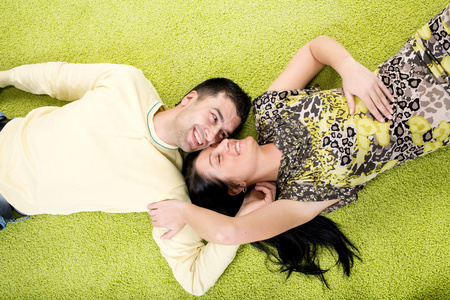 年轻幸福的一对情侣躺在地毯上