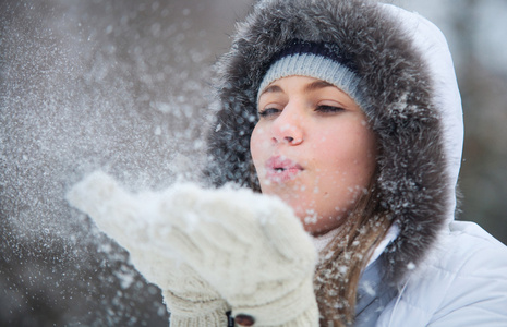 美丽的女人在雪地里吹