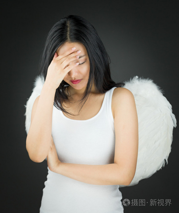 心烦意乱的亚洲年轻女人装扮成天使她的头在手