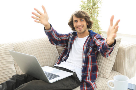 快乐的人，用一台笔记本电脑，坐在沙发上，伸出双手迎接
