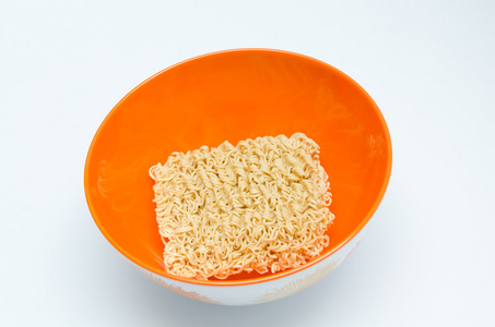 在白色背景上的橙色碗干方便面照片