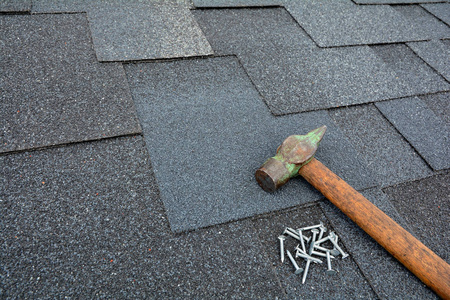 沥青油毡瓦屋顶用锤子和钉子上.关闭了沥青屋面瓦背景视图照片