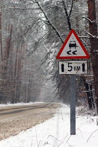冬季开车。雪冰覆盖警告标志与挡风玻璃上