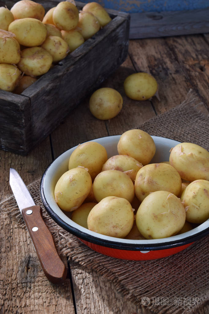 第一次收获的有机种植新土豆在碗上木制的背景.生的食物