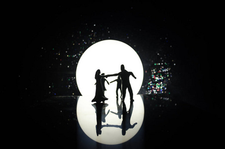 晚上在月光下跳舞的玩具夫妇的身影。数字的男人和女人在爱在月光下跳舞