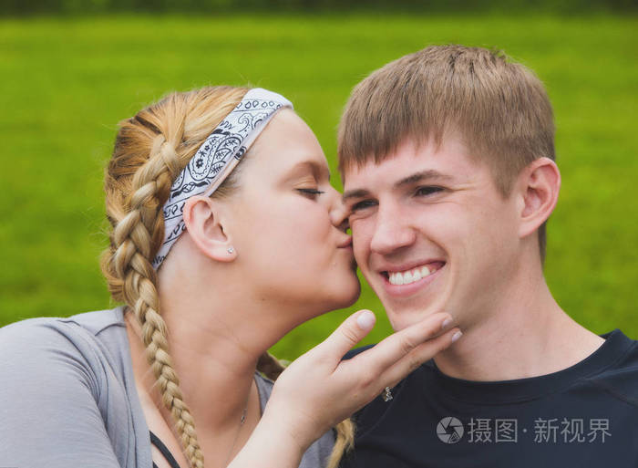 年轻爱女孩脸颊上亲吻她的男朋友