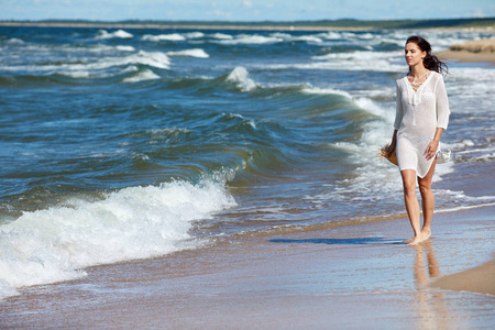 年轻女子在美丽的海滩上行走