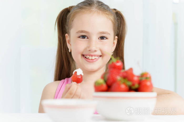 年轻可爱微笑欧洲的小女孩是吃熟阿斯内务草莓酸奶油和控股很多浆果的