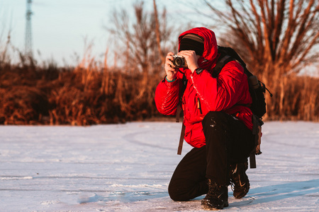 摄影师拍照在河岸边，在冬天