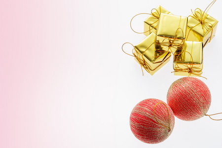 圣诞球和金色礼盒上浅粉红色背景