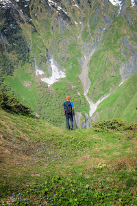 冒险家站在绿色的边坡，山峡谷
