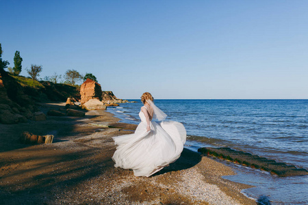 美丽的金发新娘在海边散步