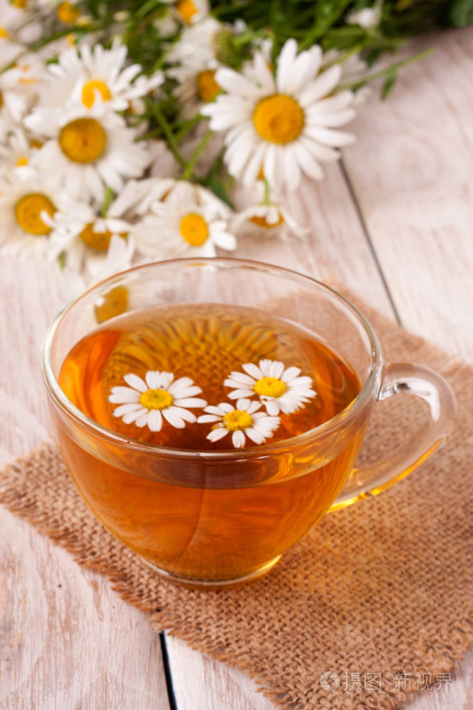凉茶与新鲜洋甘菊花白色木制背景上